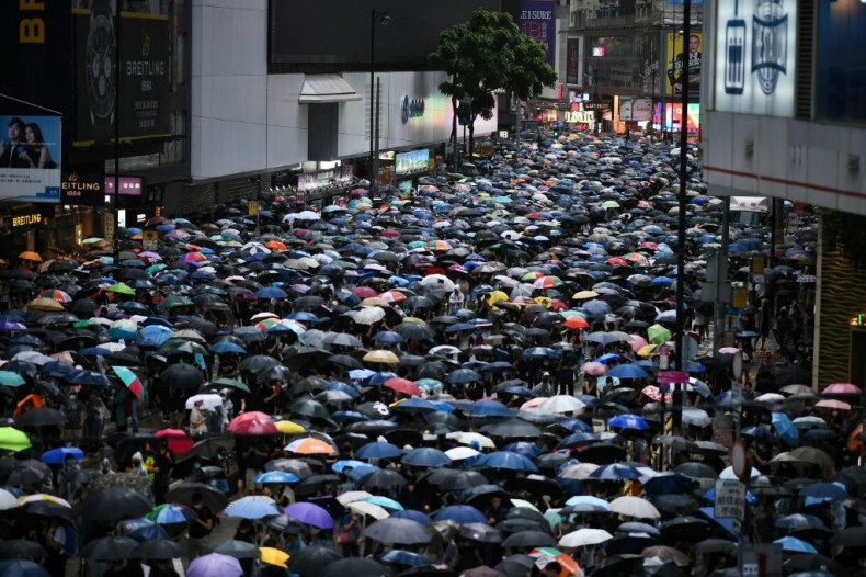 Large crowds marched through torrential rain in unsanctioned rallies on both sides of Victoria Harbour Sunday afternoon.