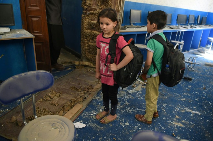 Afghan children stand in the debris at a school near the site of a Taliban car bomb attack in Kabul on July 2, 2019, a day after the deadly blast that killed at least six people and wounded dozens, including 50 children
