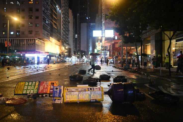 A pedestrian (C) walks past debris littering the street after protesters clashed with police in the Wanchai district in Hong Kong