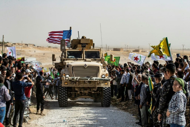 Syrian Kurds protest against a threatened Turkish military invasation next to a US armoured vehicle in Syria's Hasakeh province on October 6, 2019