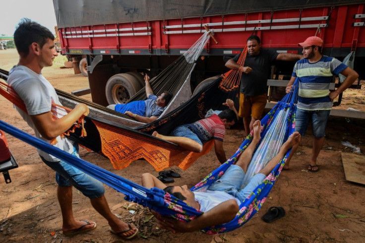 Brazilian trucker Erik Fransuer (L) speaks with other drivers resting on hammocks at a gas station in Ruropolis -- he spends at least 12 hours a day in his big rig
