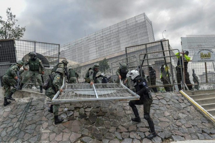 Security forces rush to erect a metal fence during clashes with demonstrators near the national assembly in Quito