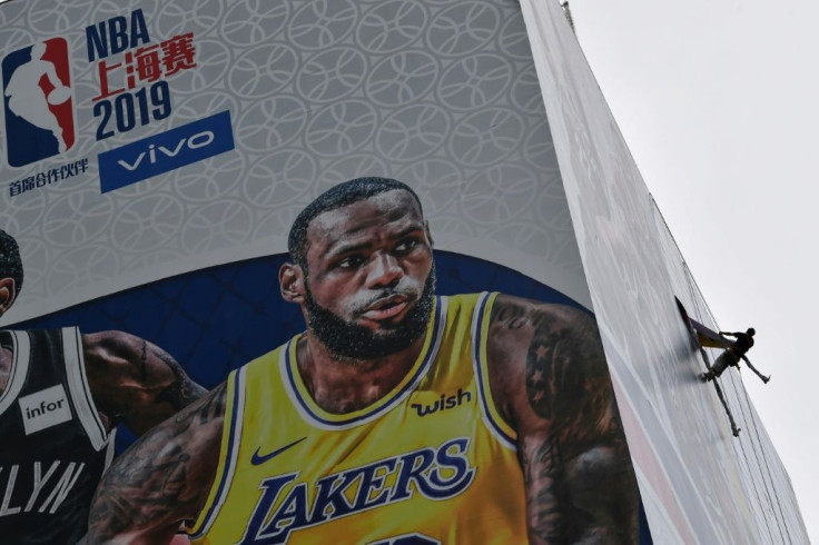 A worker on the side of a building in Shanghai removes a promotional banner for a National Basketball Association preseason game in China, after an NBA executive's comments on Hong Kong roiled ties between China and the league
