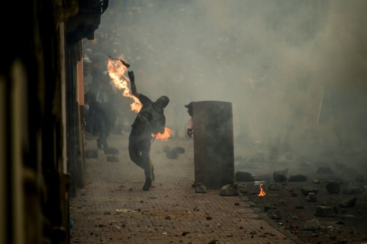 A demonstrator throws a Molotov cocktail at riot police during clashes in Quito