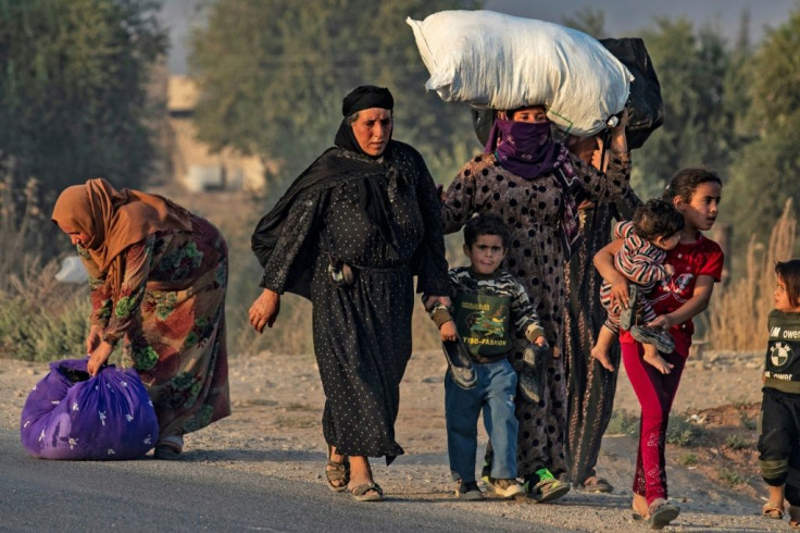 Civilians flee amid Turkish bombardment on Syria's northeastern town of Ras al-Ain in the Hasakeh province along the Turkish border on Wednesday