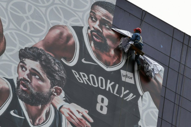 A worker removes an NBA promotional banner from a building after China shut down NBA sponsorships and telecast plans following a tweet by an NBA club executive supporting pro-democracy protesters in Hong Kong