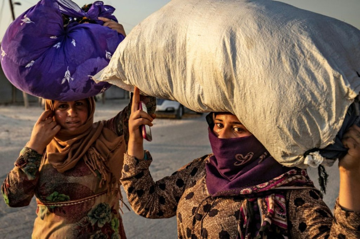 Syrian women carry what belongings they can as they flee on foot from Turkish bombardment of their Kurdish-controlled home town of Ras al-Ain