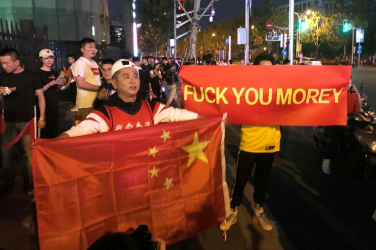 Outside the game venue, a pair of protesters held up red banners