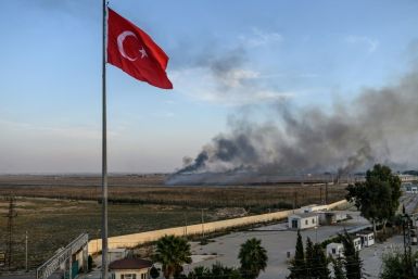 Smoke rises from the Syrian town of Tal Abyad, in a picture taken from the Turkish side of the border where the Turkish flag is seen in Akcakale on October 10, 2019, on the second day of Turkey's military operation against Kurdish forces