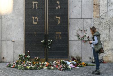 A woman stands next to flowers laid next to the entrance of the synagogue in Munich, dring a protest against anti-Semitism on October 11, 2019 two days after a deadly shooting during an attack in Halle targeting a Turkish restaurant after an attempt at th