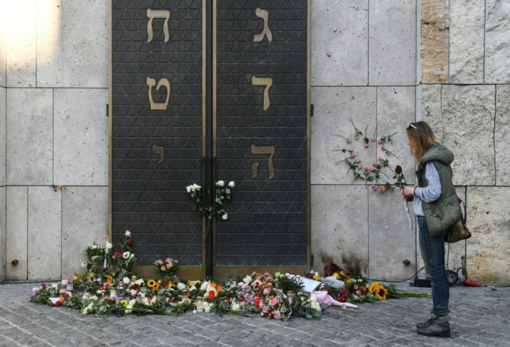 A woman stands next to flowers laid next to the entrance of the synagogue in Munich, dring a protest against anti-Semitism on October 11, 2019 two days after a deadly shooting during an attack in Halle targeting a Turkish restaurant after an attempt at th