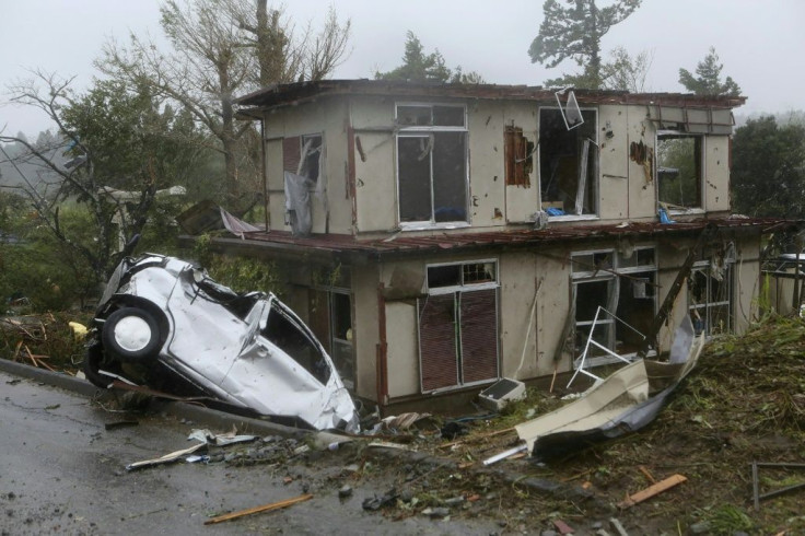 A damaged vehicle sits in a ditch next to a badly damaged house in Chiba prefecture, east of Tokyo, after strong winds brought by Typhoon Hagibis hit the area