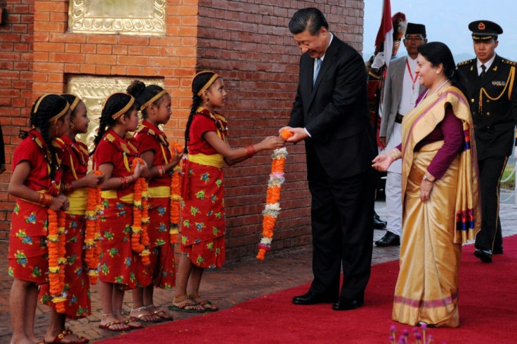 Nepalese girls present garlands to Chinese President Xi Jinping (C) as Nepal's president Bidhya Devi Bhandari (R) looks on during a welcome ceremony at the Tribhuvan International Airport in Kathmandu