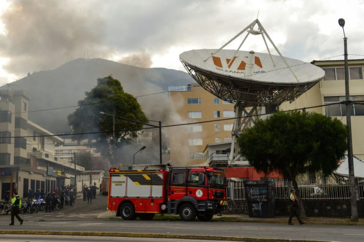Firefighters work to extinguish a blaze at TV station Teleamazonas after it was attacked by demonstrators