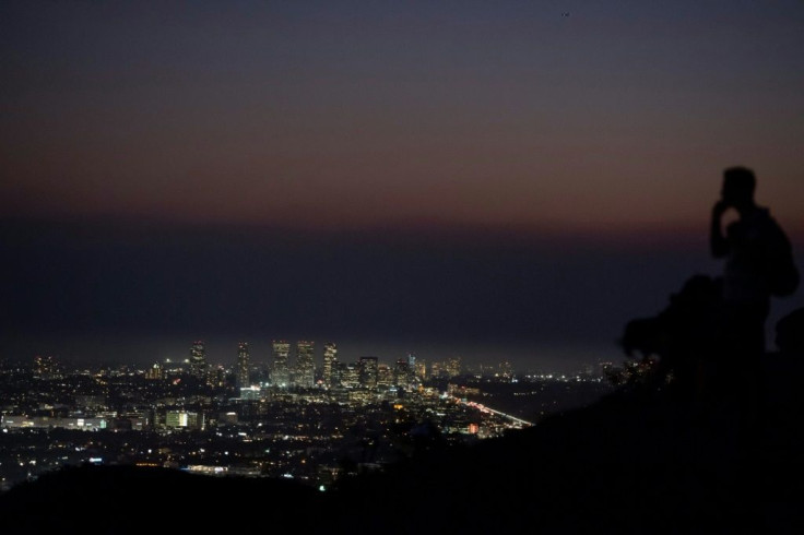 A hiker in Griffith Park looks toward the Century City neighborhood of Los Angeles where a layer of smoke from the Saddleridge fire hangs over tall buildings on October 11, 2019