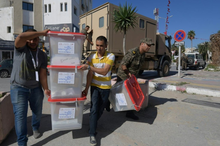 Men from Tunisia's election commission and members of the military deliver blank ballots to a polling station in the capital a day before the presidential runoff