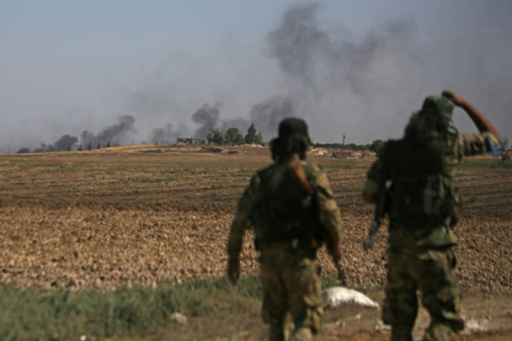 Turkish-backed Syrian fighters watch as smoke billows from the Syrian border town of Tal Abyad