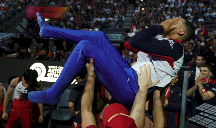 Britain's Joe Fraser is hoisted into the air by team-mates after winning the men's parallel bars world title in Stuttgart