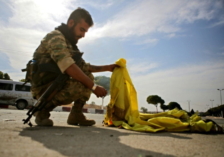 A Turkish-backed Syrian fighter burns the flag of the Kurd-led SDF