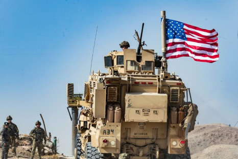 A US soldier sits atop an armored vehicle during a demonstration by Syrian Kurds in the town of Ras al-Ain shortly before the Turkish invasion in October 2019