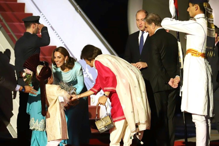 Britain's Prince William, Duke of Cambridge (3R), and his wife Kate (2L) receive flowers from Pakistani children after arriving at a military airbase in Rawalpindi for the first visit by British royals since 2006