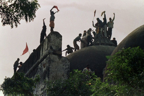Hindu fundamentalists shout and wave banners as they stand on the top of a stone wall and celebrate the destruction of the 16th century Babri Mosque in Ayodhya in 1992