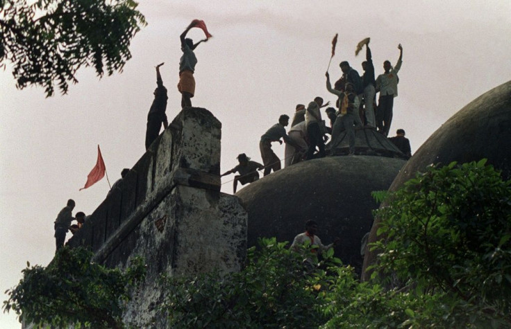 Hindu fundamentalists shout and wave banners as they stand on the top of a stone wall and celebrate the destruction of the 16th century Babri Mosque in Ayodhya in 1992