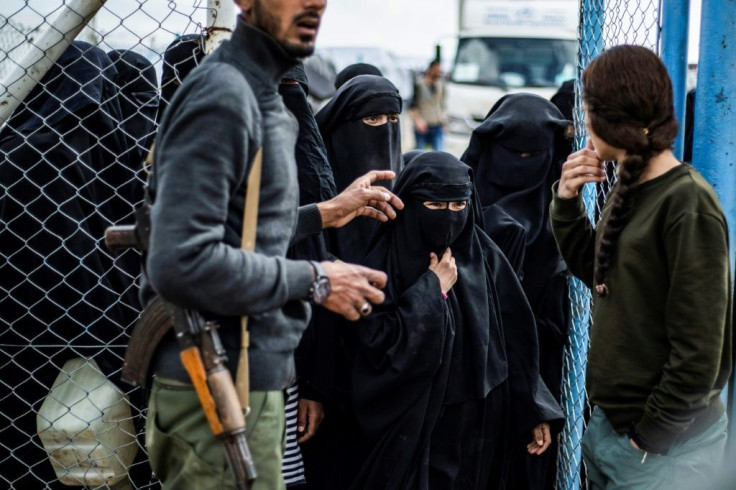 Members of the Syrian Democratic Forces stand guard over veiled women in al-Hol camp in northeastern Syria, which houses relatives of Islamic State group members