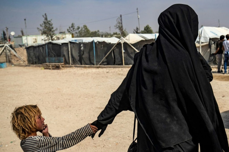 A French woman held at Al-Hol camp holds a child by the hand