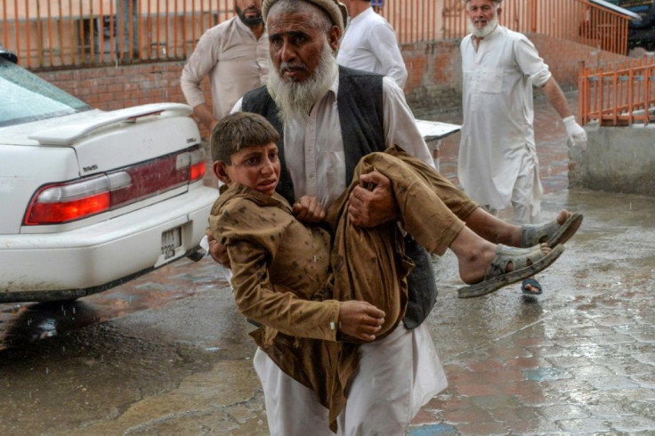 A volunteer in Afghanistan carries an injured youth to hospital following the country's second-deadliest blast of the year, in Nangarhar Province