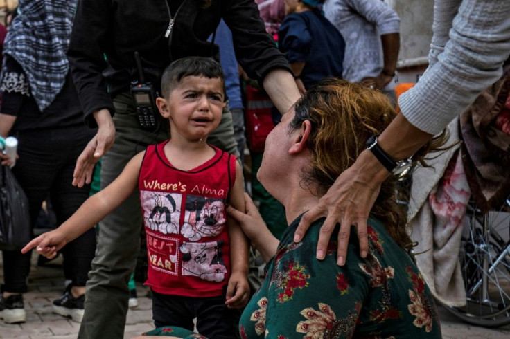 A woman and a child react as the body of a man killed during Turkish shelling near the Syrian Kurdish town of Ras al-Ain arrives at a hospital in the nearby town of Tal Tamr