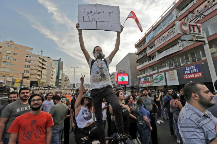 A protestors raises a sign reading "you're burning our future" at a protest north of Beirut