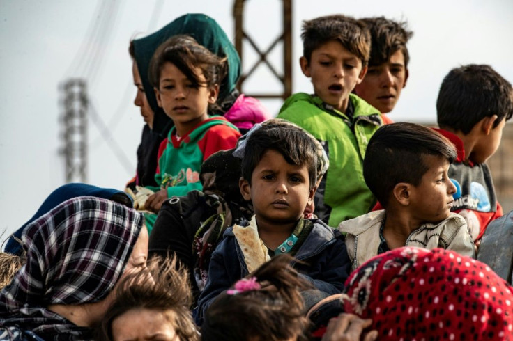 Syrian women and children flee the countryside of the northeastern Syrian town of Ras al-Ain on the Turkish border