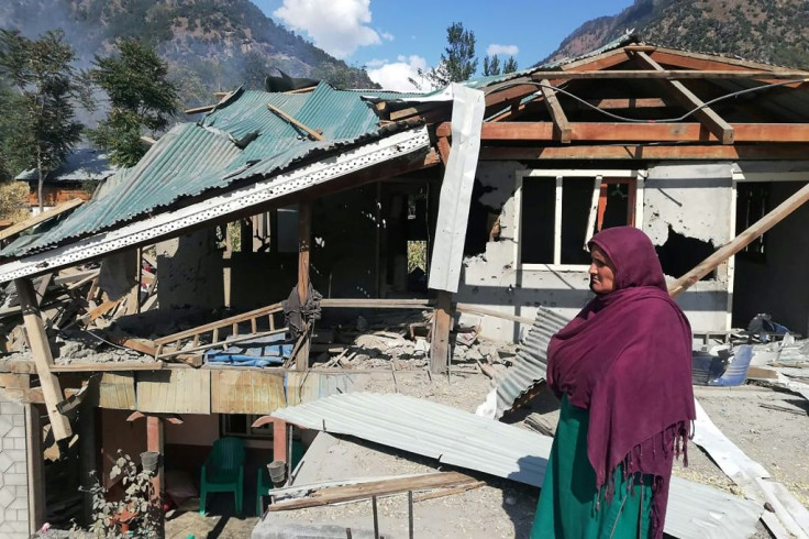 A resident in Jora, a Neelum valley village in Pakistan-administered Kashmir, stands by her home damaged by cross border shelling