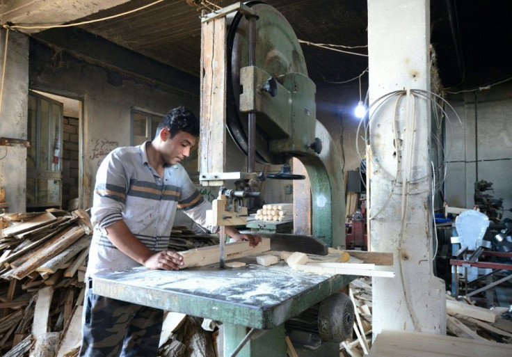An Iraqi man cuts wood with a band saw at a lumber mill in northern Mosul as the city's manufacturers struggle to recover from three years of brutal jihadist rule under the Islamic State group that ended in mid-2017
