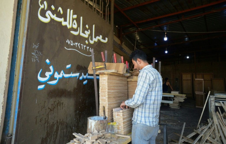 An Iraqi carpenter at a furniture factory in northern Mosul where factories are still rebuilding, export routes are choked by informal customs points, and cheap imports flood the market