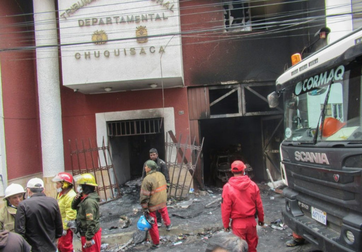 Firefighters survey the wreckage of the electoral authority headquarters in the southern city of Sucre after poll results that appeared to hand victory to incumbent president Evo Morales sparked riots