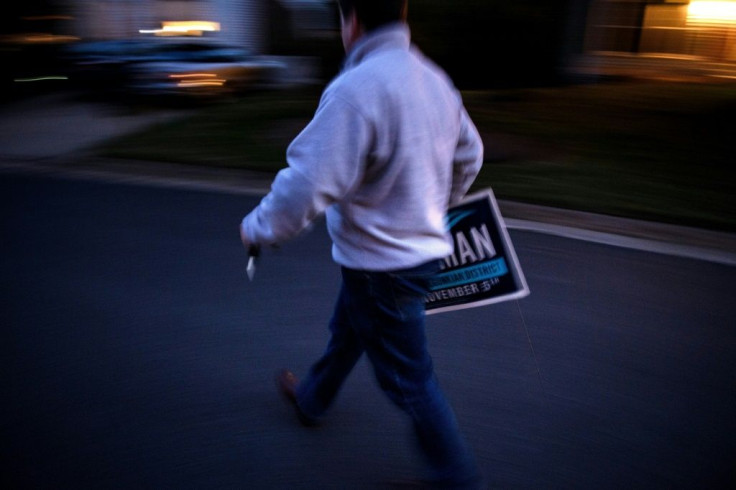 Mike Mullins, Juli Briskman's campaign manager, goes to set up a sign in a supporter's garden