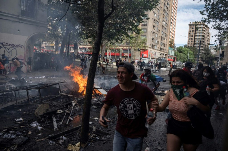 People run during clashes at Plaza Italia in Santiago on October 22