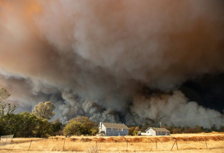 A home is overshadowed by towering smoke plumes as the Camp Fire raced through Paradise, California in November 2018