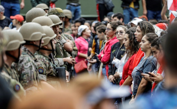 Women form a line in front of Lebanese army soldiers during a demonstration on the seventh day of protests against tax increases and official corruption