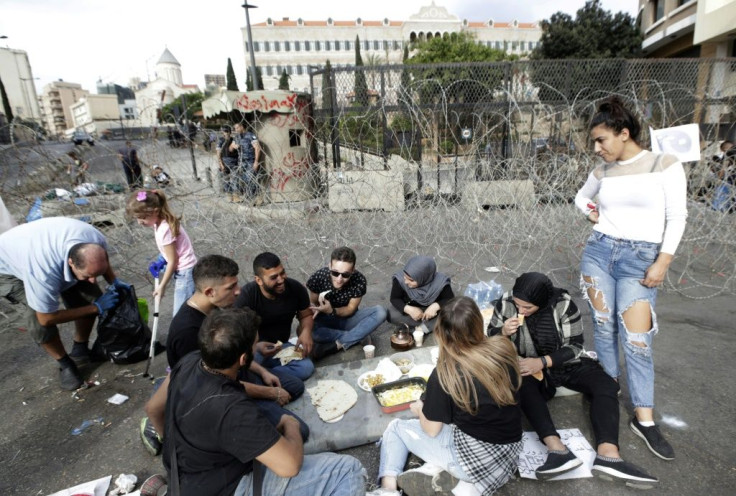 Lebanese protestors share a meal near barbed wire set up to protect the government palace