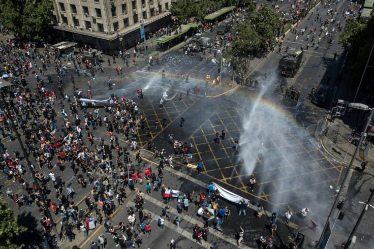 Riot police use water cannons on demonstrators in Santiago, on the sixth straight day of street violence in Chile, which has left at least 18 people dead