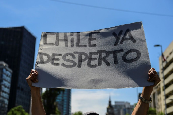 A demonstrator in Santiago holds a sign reading 'Chile has awakened'