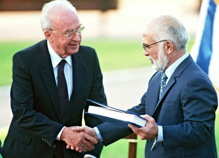Jordan's King Hussein (R) and Israeli Premier Yitzhak Rabin shake hands after exchanging the documents of the peace treaty on the southern shore of the Sea of Galilee