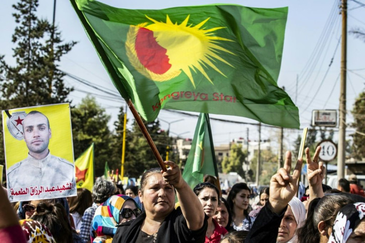 Syrian Kurds carrying photographs of loved ones killed in the Turkish offensive protest against the carve-up of their northeastern heartland by Ankara and Moscow
