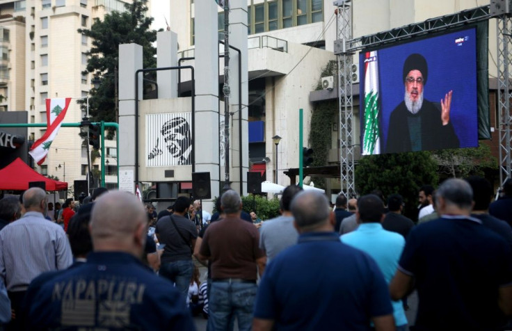 Lebanese anti-government protesters listen to a televised speech by Hassan Nasrallah, the head of the powerful Shiite Hezbollah movement who has warned of "chaos" if the cabinet resigns