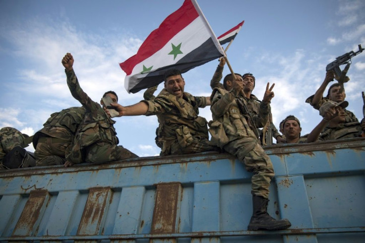Syrian government forces drive along a road in the countryside of the northeastern Syrian city of Qamishli