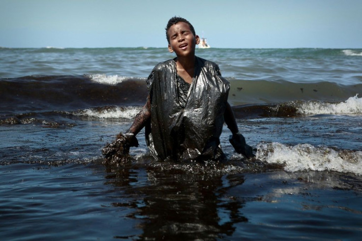 A boy wades ashore covered with oil on Itapuama beach in northeast Brazil on October 21