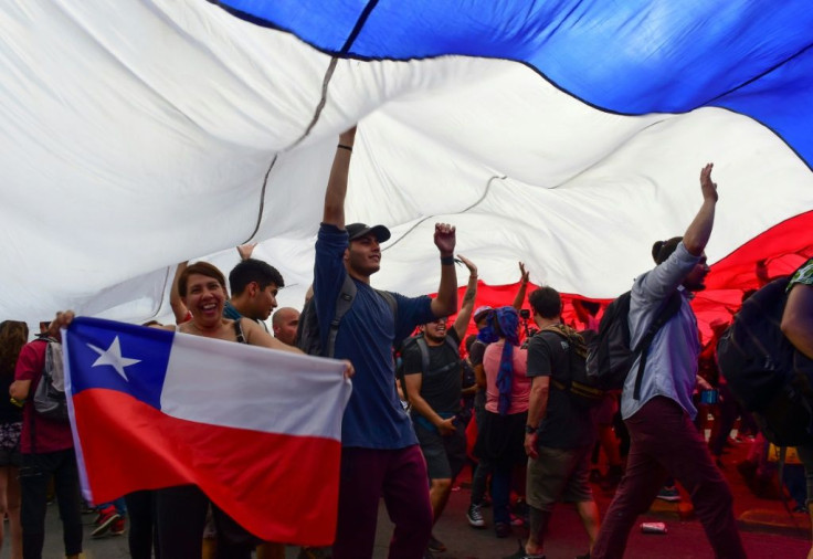 People protest under a giant Chilean national flag in Santiago, on October 25